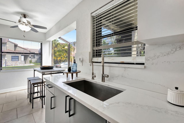 kitchen featuring light stone counters, plenty of natural light, a sink, and light tile patterned flooring