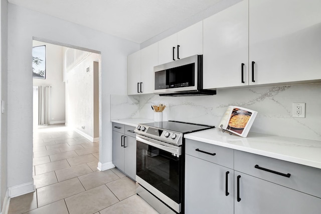 kitchen with stainless steel appliances, white cabinets, backsplash, and light tile patterned flooring