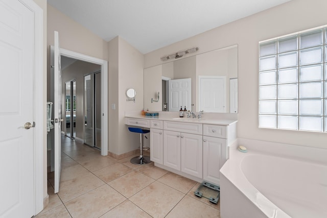 full bathroom featuring vanity, tile patterned flooring, a bath, and baseboards