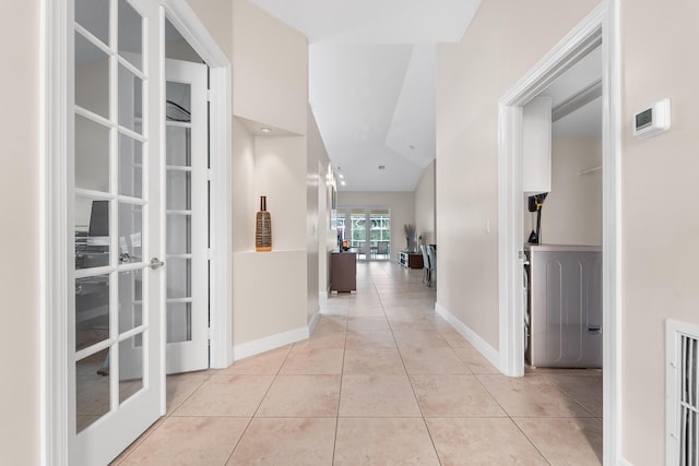 hall with light tile patterned floors, french doors, and baseboards