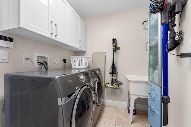 washroom with cabinet space, washer and clothes dryer, baseboards, and light tile patterned floors