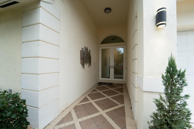 view of exterior entry featuring a garage, stucco siding, and french doors