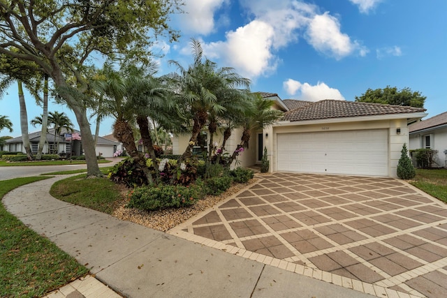 view of front of home featuring driveway, an attached garage, a tile roof, and stucco siding