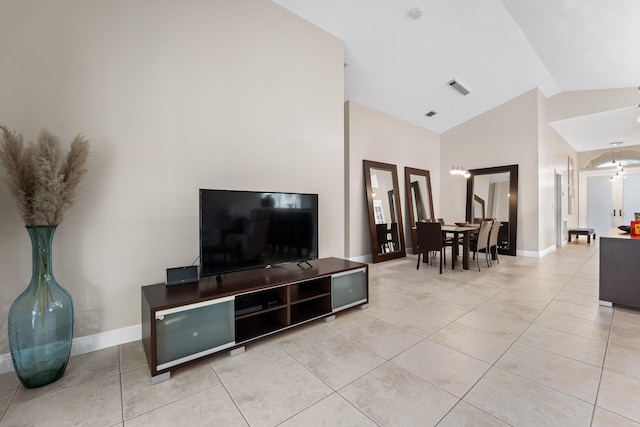 living area featuring light tile patterned floors, baseboards, vaulted ceiling, and a notable chandelier