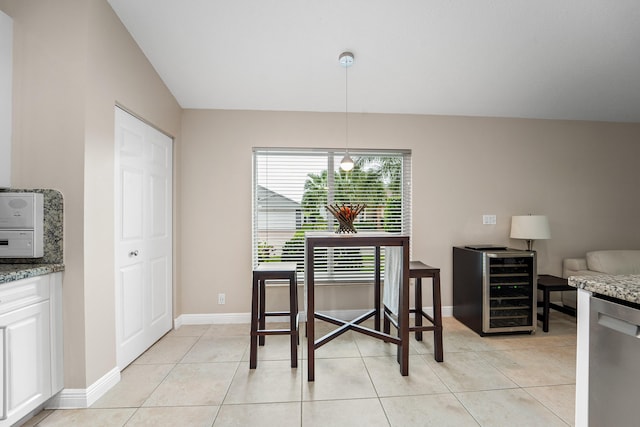 dining space featuring beverage cooler, baseboards, and light tile patterned floors