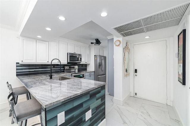 kitchen with light stone counters, a breakfast bar, marble finish floor, appliances with stainless steel finishes, and a sink