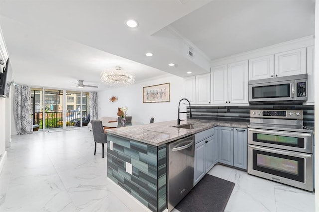 kitchen featuring stainless steel appliances, a peninsula, a sink, marble finish floor, and crown molding