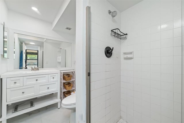 bathroom featuring toilet, marble finish floor, tiled shower, and vanity