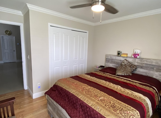 bedroom featuring a closet, ornamental molding, ceiling fan, wood finished floors, and baseboards