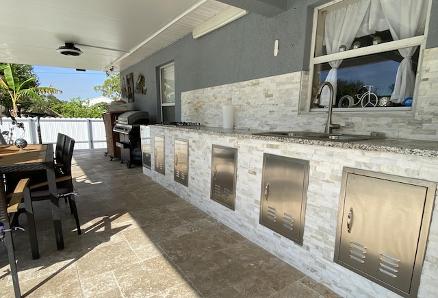 view of patio / terrace featuring area for grilling, ceiling fan, grilling area, fence, and a sink