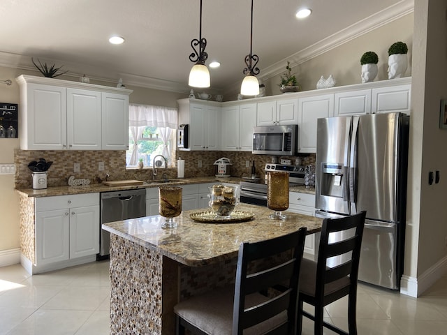 kitchen with stainless steel appliances, light stone counters, a kitchen island, and white cabinetry