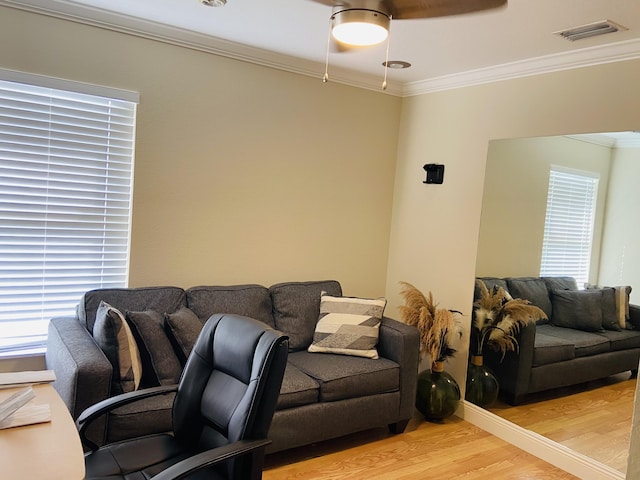 living room featuring light wood-type flooring, a healthy amount of sunlight, visible vents, and ornamental molding