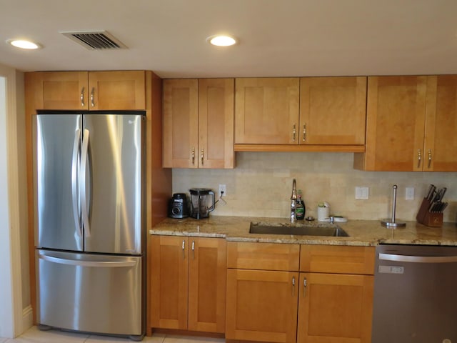 kitchen with stainless steel appliances, light stone counters, backsplash, recessed lighting, and a sink