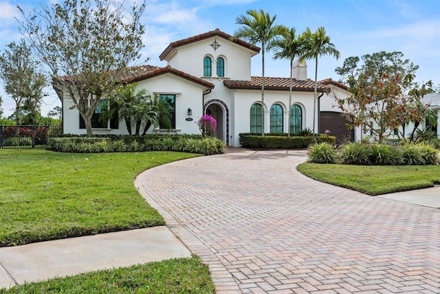 mediterranean / spanish house featuring a garage, a tiled roof, decorative driveway, a chimney, and a front yard