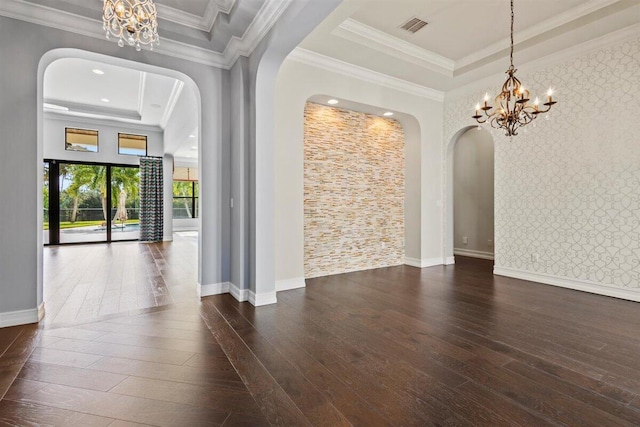 empty room with ornamental molding, a raised ceiling, visible vents, and wood-type flooring