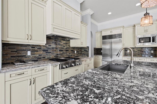 kitchen with built in appliances, a sink, cream cabinetry, backsplash, and crown molding