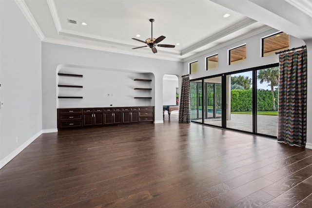 unfurnished living room with dark wood-style floors, a tray ceiling, and ornamental molding