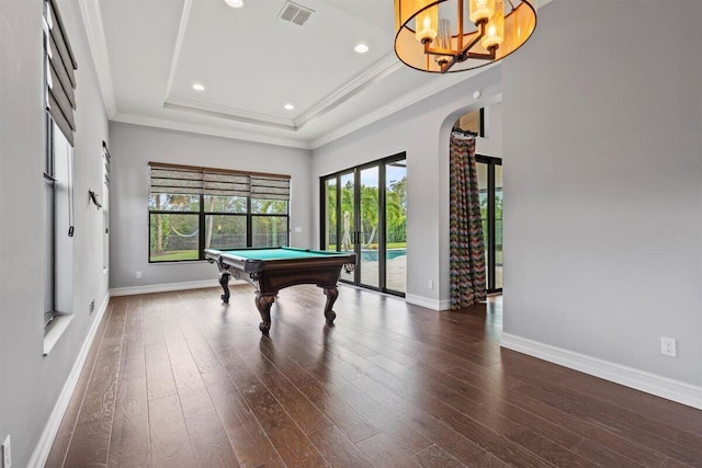 rec room with arched walkways, wood finished floors, baseboards, a raised ceiling, and crown molding