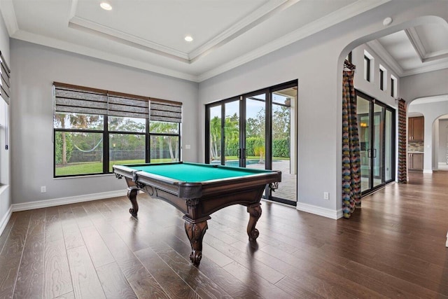 rec room featuring dark wood-style floors, arched walkways, a raised ceiling, ornamental molding, and baseboards