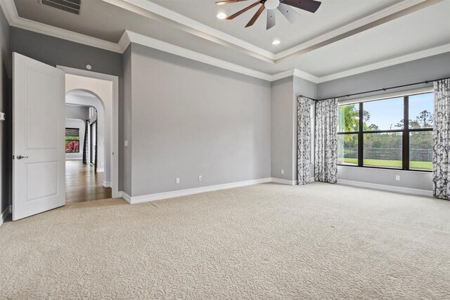 carpeted empty room featuring arched walkways, ornamental molding, visible vents, and baseboards