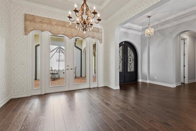 entrance foyer with arched walkways, french doors, and wallpapered walls