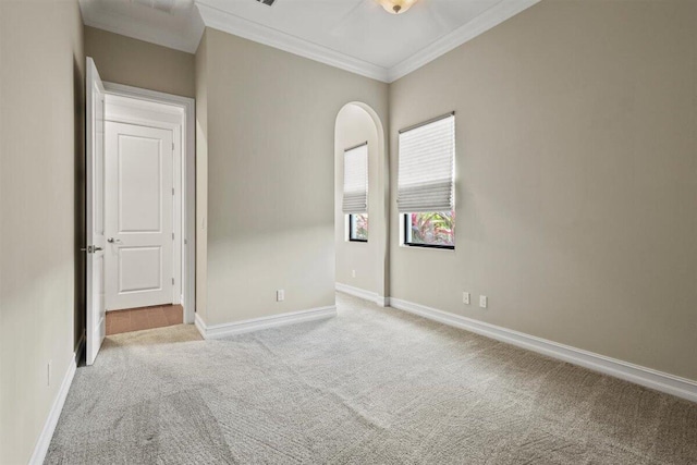 empty room with carpet flooring, crown molding, and baseboards