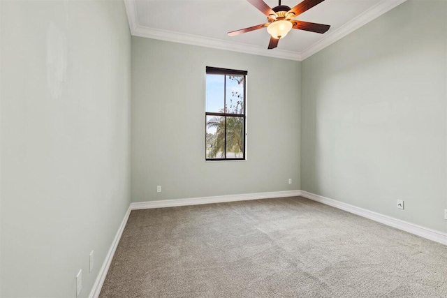 carpeted spare room with ornamental molding, baseboards, and a ceiling fan