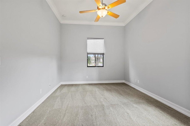 carpeted spare room with ceiling fan, baseboards, and crown molding