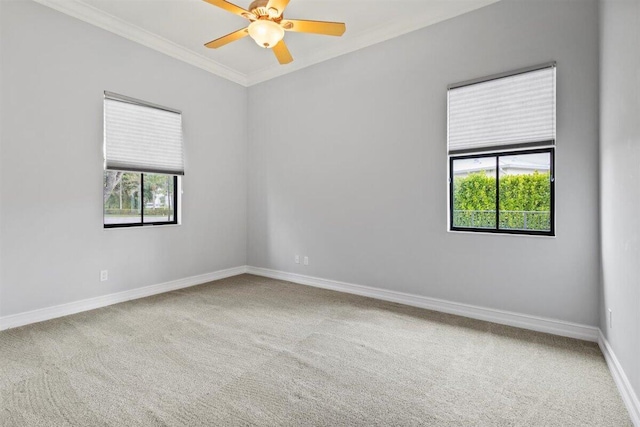 empty room with ornamental molding, carpet flooring, baseboards, and a ceiling fan