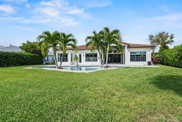 back of property featuring a yard, a tile roof, a fenced in pool, and stucco siding