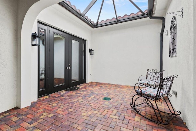 property entrance with french doors, a tiled roof, and stucco siding