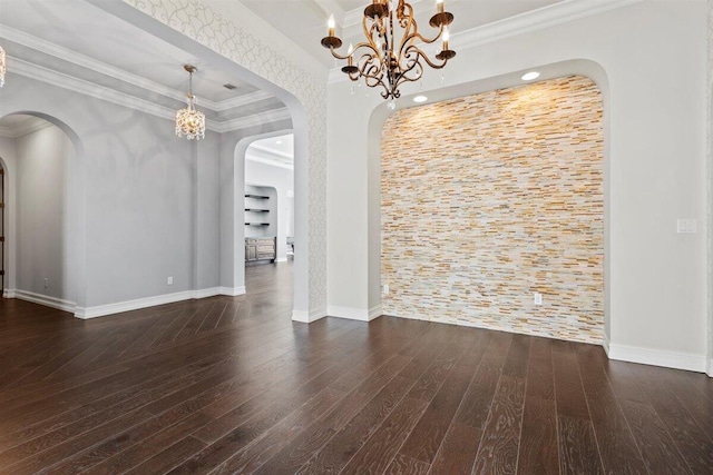 unfurnished dining area with baseboards, ornamental molding, wood finished floors, and an inviting chandelier