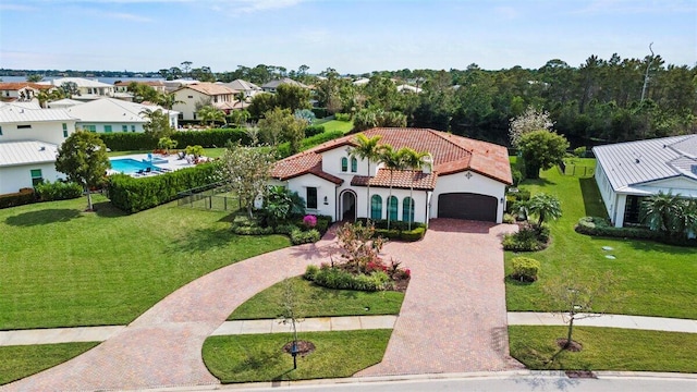 view of front of property featuring decorative driveway, a tile roof, fence, and a front lawn