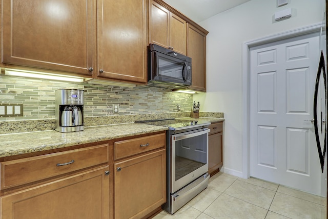 kitchen with light tile patterned floors, electric stove, light stone counters, and backsplash