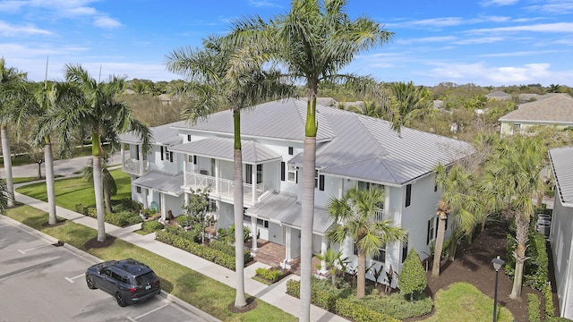 view of front of house featuring metal roof, uncovered parking, and a balcony