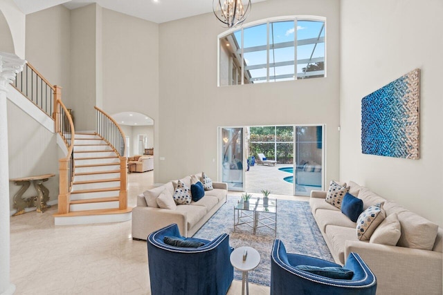 living area featuring arched walkways, a notable chandelier, a towering ceiling, and stairs