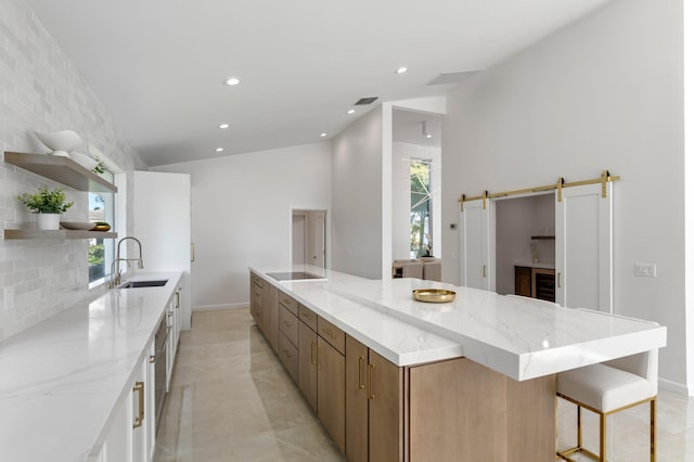 kitchen with a barn door, white cabinetry, open shelves, and a sink