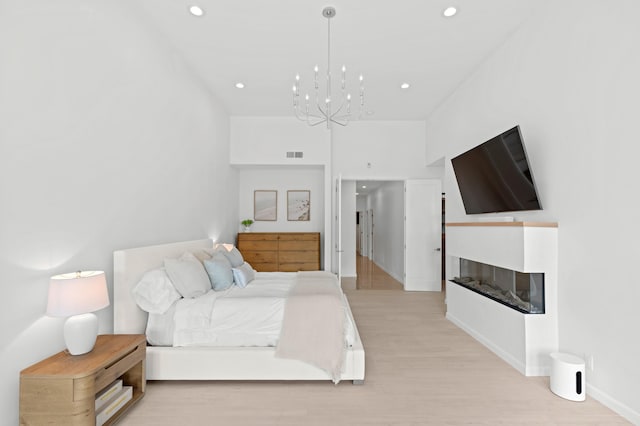 bedroom featuring light wood-type flooring, visible vents, a multi sided fireplace, and recessed lighting