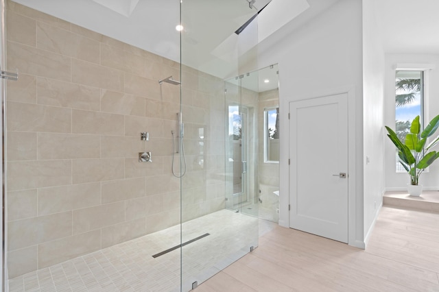 bathroom with a walk in shower, wood finished floors, and baseboards