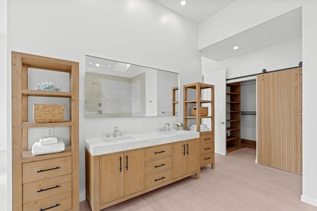 bathroom with recessed lighting, a walk in closet, a sink, and double vanity