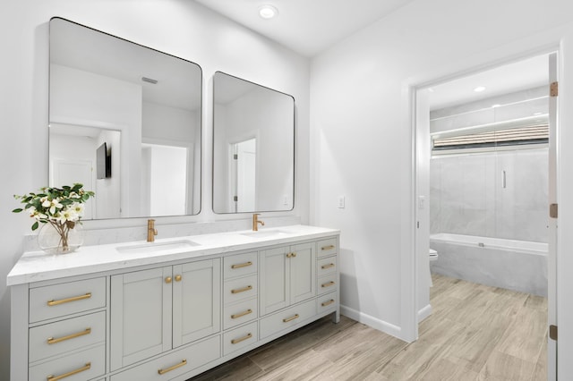 bathroom with double vanity, a sink, and wood finished floors