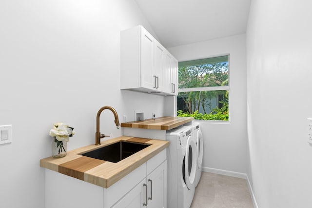 laundry area featuring cabinet space, baseboards, a sink, and washing machine and clothes dryer