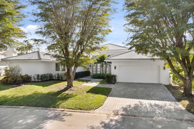 view of front of home featuring a garage, a front yard, decorative driveway, and a tiled roof