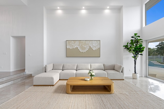 living area featuring a high ceiling, baseboards, and recessed lighting