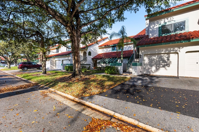 view of front of home with a tiled roof, aphalt driveway, an attached garage, and stucco siding