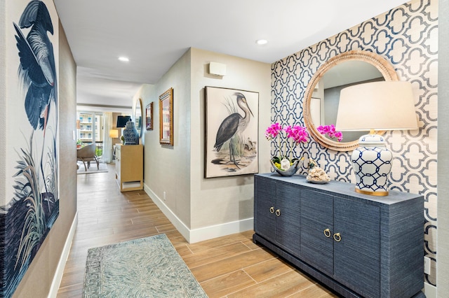 hallway featuring wood tiled floor, recessed lighting, baseboards, and wallpapered walls