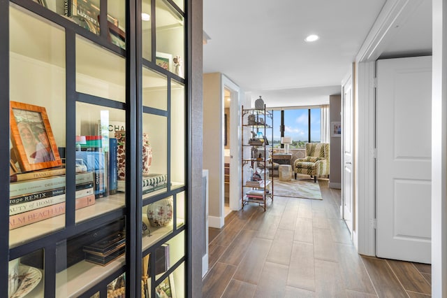 hall featuring wood finish floors, floor to ceiling windows, and recessed lighting