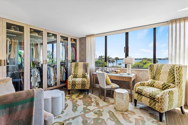 sitting room featuring a water view, light wood finished floors, and wallpapered walls