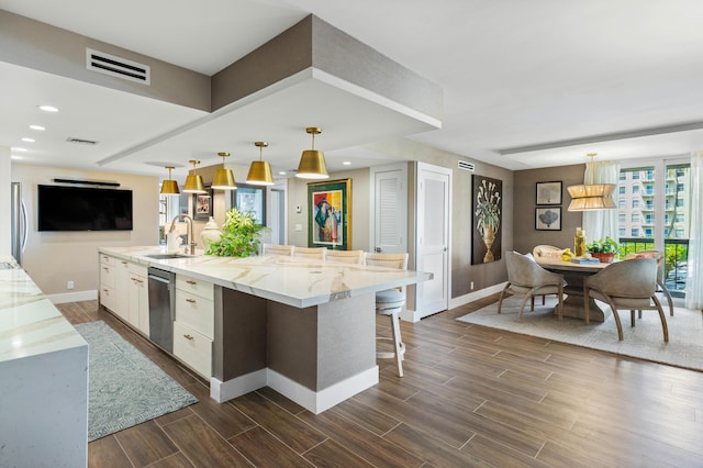 kitchen with visible vents, a spacious island, white cabinetry, pendant lighting, and a sink