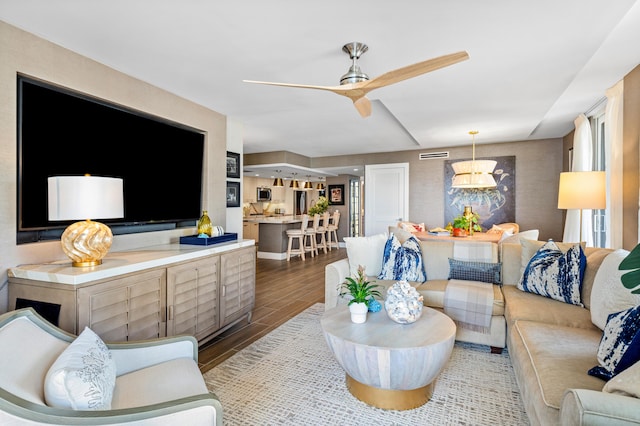 living room featuring a ceiling fan and dark wood-style flooring